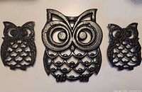 Front view of three owl cast iron trivets