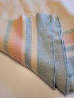 Folded wool blanket showing pastel stripes and edge stitching