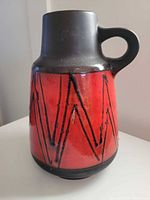 Front view of ceramic handled vase showing red glaze and black zig-zag design