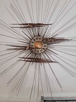 Full view of mixed-metal starburst sculpture on wall