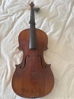Full front view of violin showing varnish color, f-holes, missing bridge and strings