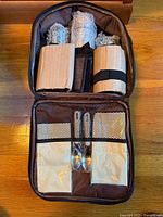 Open Gevalia travel set in brown case showing packaged contents and mesh pockets with spoons