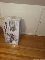 Two sealed retail boxes of Hamilton Beach Quick Dry 4-Shelf Garment Drying Station standing on hardwood floor