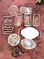 All pieces arranged on carpet showing loaf pans, casseroles, lids, ceramic baker, rack, saucepan, mixing bowl