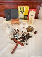 Group shot showing books, music box, candle, scapulars, crucifixes, plaque, coin