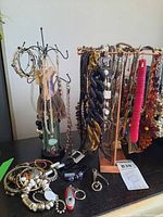 Overall lot showing necklaces, bracelets, keychains and two jewelry stands