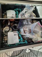Drawer containing turquoise bead strands, metal bangles, bracelets in plastic bags