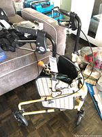 Overall view of yellow Drive Winnie Lite Supreme 3-wheel walker with plaid pouch and umbrellas inside basket