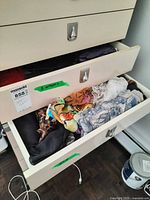Two dresser drawers open showing mixed scarves and gloves