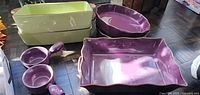 Stacked green rectangular dishes, purple oval dishes, purple soup bowls and purple rectangular dish