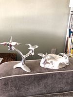 Both Hoselton aluminum bird sculptures on sofa back, showing overall forms and bases