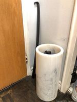 Marble umbrella stand with shoehorn beside it