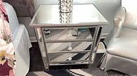 Front view of mirrored nightstand showing three drawers and crystal knobs