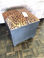 Overall view of cube ottoman showing leopard print lid and black sides
