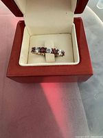 Ring in presentation box front view showing red and clear stones
