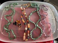 overview of all necklaces and brooch in plastic bin