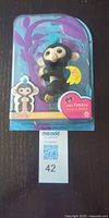 Front view of sealed Fingerlings baby monkey toy showing character and packaging
