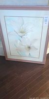 Full view of framed floral print leaning against wall