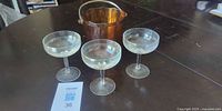 Amber glass mini ice bucket with three clear coupe glasses displayed on table