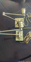 pair of brass swing-arm wall lights coiled on table