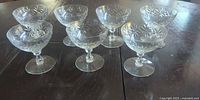 Seven matching cut glass coupes on table