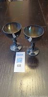 Pair of silver goblets on tabletop with lot tag visible
