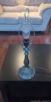 Full view of metal lamp with bulb and harp