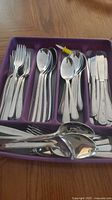 Top view showing forks, spoons, knives and serving spoons in purple tray