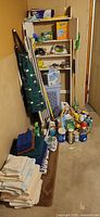 Overview of lot with ironing board, mop, broom, hamper, shelf, cleaning bottles