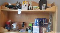 Overall view of shelf showing figurines, candles, LED bulb boxes and various small décor pieces