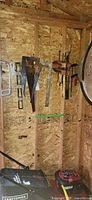 Overall view of tools hanging: hand saws, square, chisels, level, clamp, pruners