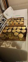 Three cardboard trays of yellow daisy glass jars with metal lids