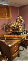 Full view of brown Wildfire ride horse on metal spring frame positioned on wooden desk