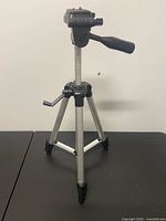Tripod front view, legs extended mid-range, pan handle visible