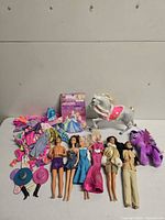 Group shot of six dolls, grey horse, purple plush pony, clothing pile, hats and Disney card backing
