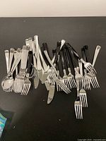 overview of mixed toy cutlery pile on black surface
