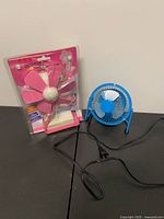 Supa Fine fan in package beside ZhiLang metal fan with cord