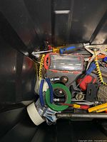 Top view of bin showing mixed tools, tape, pliers, hardware