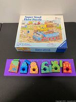 Ravensburger puzzle box and wooden train puzzle board side by side