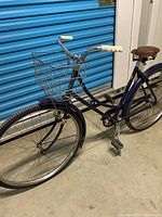 Full view of blue-violet Raleigh step-through bicycle with basket