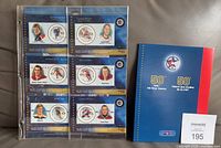 Front view of six stamp cards in plastic sleeve alongside blue booklet