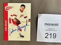 Front of signed John Bucyk Parkhurst card next to Maxsold lot tag