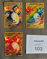 Front view of three golden metal Charizard VMAX cards showing artwork and numbers
