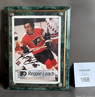 Front view of signed Reggie Leach photo on plaque with MaxSold lot card