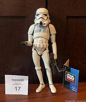 Front view of figure with helmet on, blaster in hand, hang tag visible.