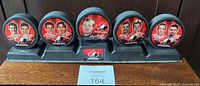 Front view of five pucks on stand showing player portraits