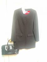 Front view of black jacket hung on hanger above black patent handbag