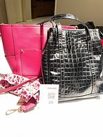 Pink Nanette Lepore bag with straps and black faux croc tote side by side