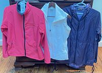 Three outerwear pieces displayed together on hangers