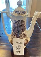 Full view of tall coffee pot with landscape pattern and lid